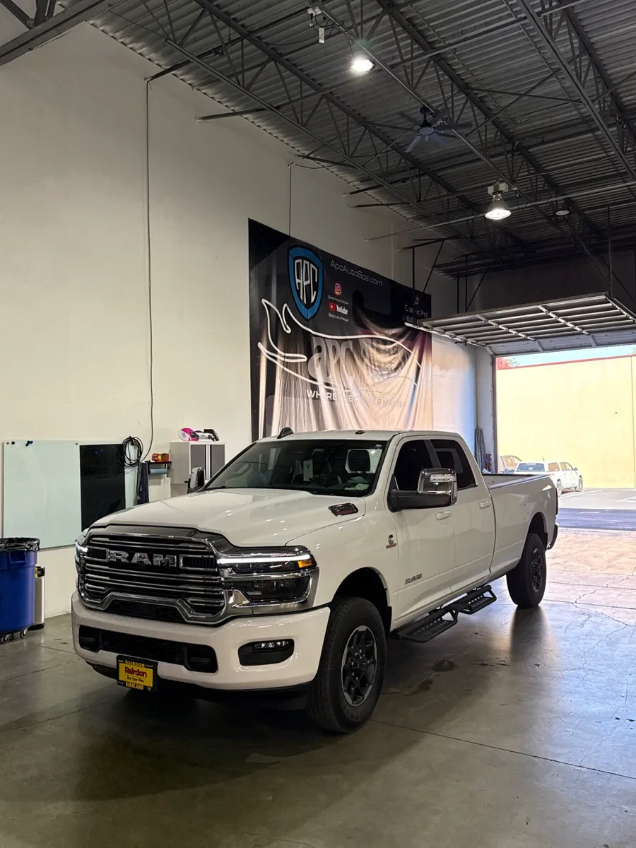 White RAM 3500 pickup truck with tinted windows parked inside the APC Auto Spa shop