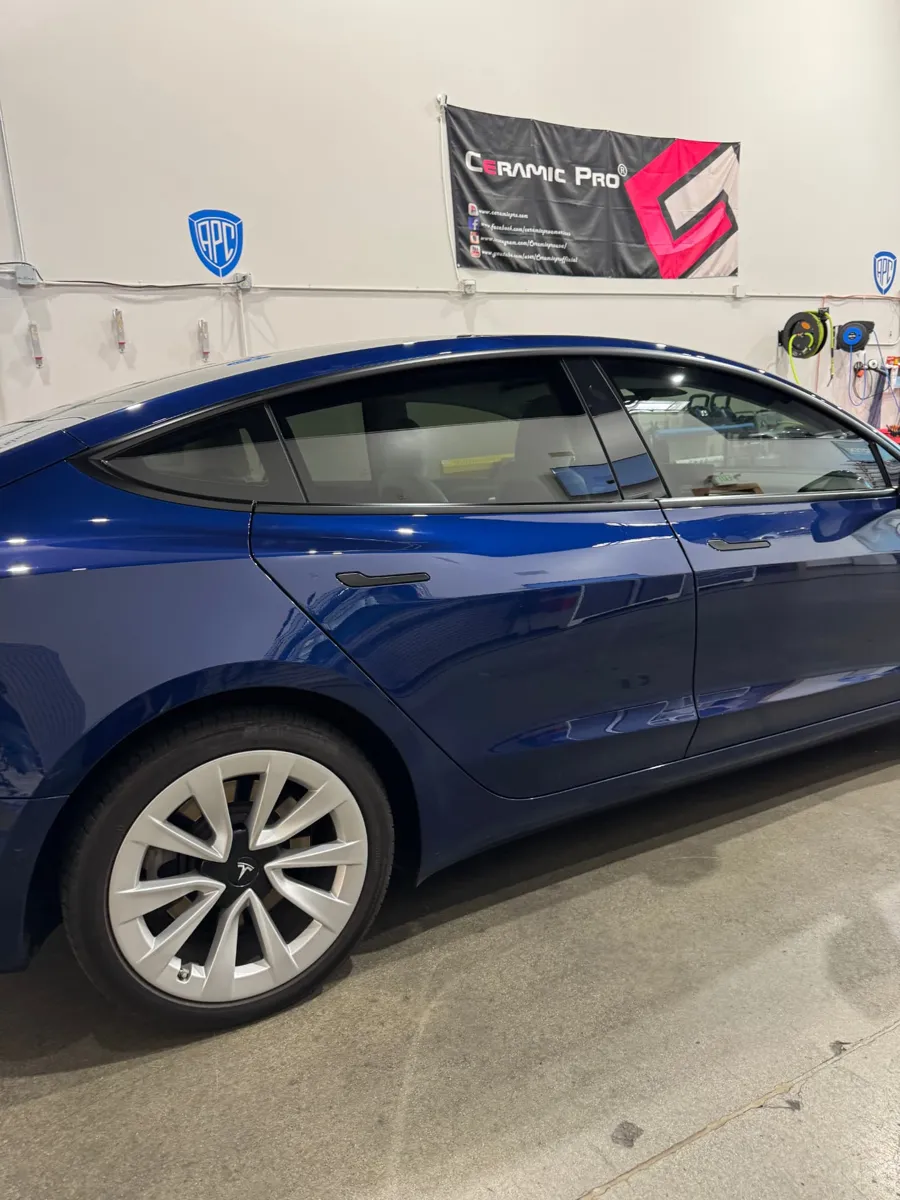 Blue Tesla Model 3 with tinted rear side windows inside the APC Auto Spa shop