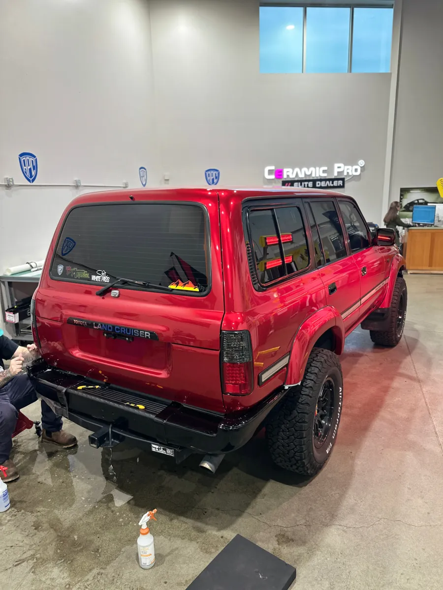 Red Toyota Land Cruiser with tinted side windows and back glass inside the APC Auto Spa shop